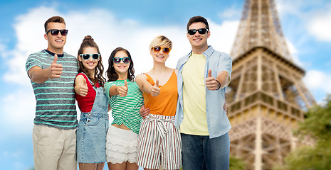 Image showing happy friends showing thumbs up over eiffel tower