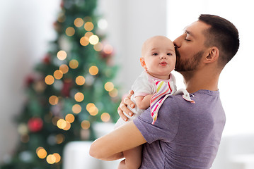 Image showing father kissing baby daughter over christmas tree