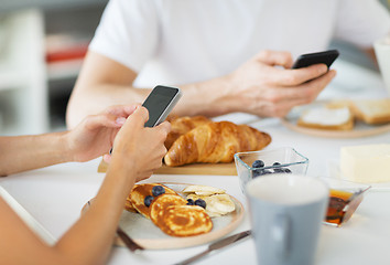 Image showing close up of couple with smartphones at breakfast