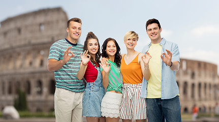 Image showing happy friends showing ok hand sign over coliseum