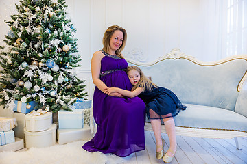 Image showing Beautiful pregnant woman in ultra violet dress sitting with doughter