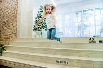 Image showing Cute girl in in casual clothes jumping from staircase