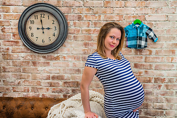 Image showing Beautiful pregnant woman sitting near wall