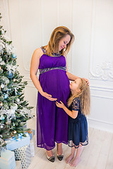 Image showing Beautiful pregnant woman in ultra violet dress standing with doughter
