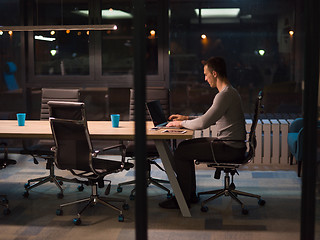 Image showing man working on laptop in dark office