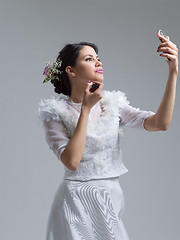 Image showing bride paints lips with lipstick