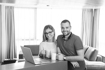 Image showing couple drinking coffee and using laptop at home