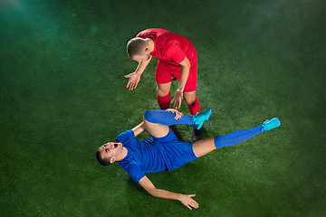 Image showing Male soccer player suffering from leg injury on football green field