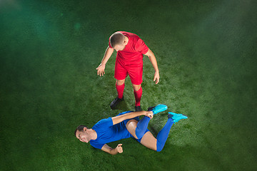 Image showing Male soccer player suffering from leg injury on football green field