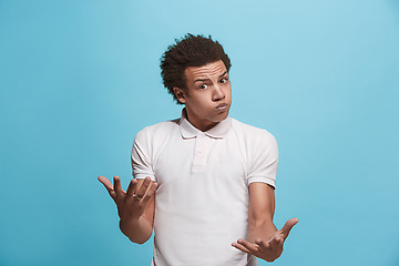 Image showing Beautiful male half-length portrait isolated on blue studio backgroud. The young emotional afro man