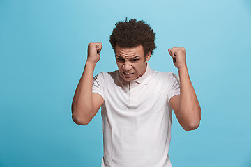 Image showing The young emotional angry man screaming on blue studio background