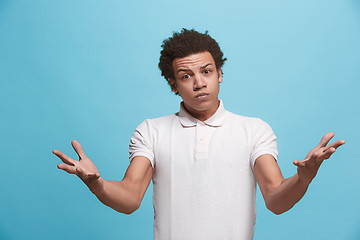 Image showing Beautiful male half-length portrait isolated on blue studio backgroud. The young emotional afro man