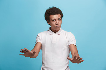 Image showing Beautiful male half-length portrait isolated on blue studio backgroud. The young emotional afro man