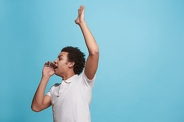 Image showing Isolated on blue young casual man shouting at studio