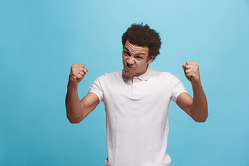 Image showing The young emotional angry man screaming on blue studio background