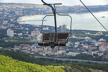 Image showing Seats of cable car to mountains against backdrop of sea city below