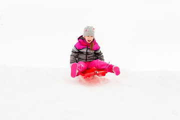 Image showing happy little girl sliding down on sled in winter