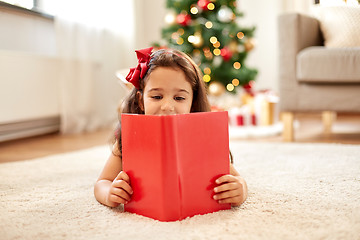 Image showing happy girl reading book at home on christmas