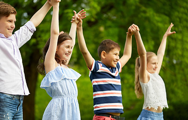 Image showing happy kids holding raised hands in summer park