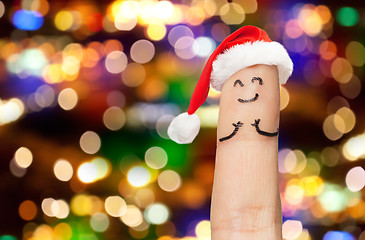 Image showing close up of finger in santa hat over lights