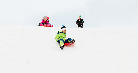 Image showing kids sliding on sleds down snow hill in winter