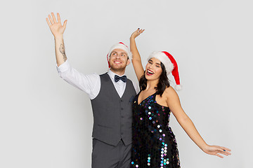 Image showing happy couple in santa hats at christmas party