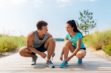 Image showing couple of joggers tying sneakers shoelaces