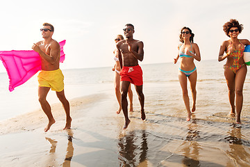 Image showing friends run with beach ball and swimming mattress