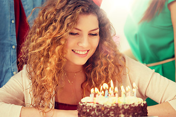 Image showing happy woman with candles on birthday cake at party