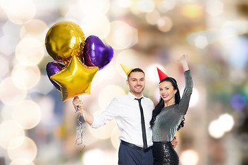 Image showing happy couple with party caps and balloons