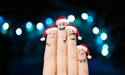 Image showing close up of four fingers in santa hats over lights