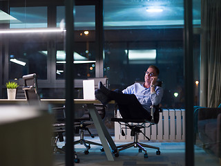 Image showing businessman using mobile phone in dark office