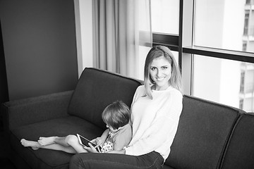 Image showing mother and her cute little daughter are using a tablet