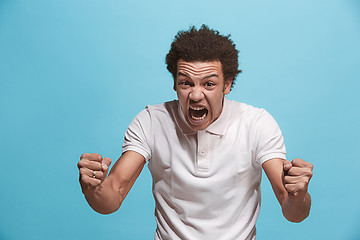 Image showing The young emotional angry man screaming on blue studio background