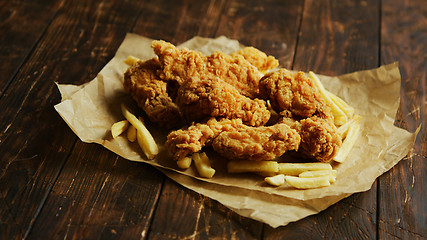 Image showing French fries and chicken wings on parchment