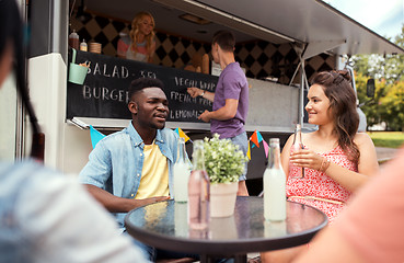 Image showing friends with drinks sitting at table at food truck