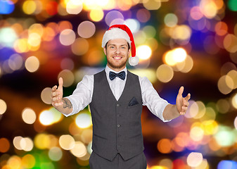 Image showing happy man in santa hat holding something imaginary