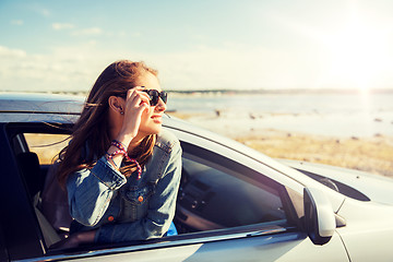 Image showing happy teenage girl or young woman in car