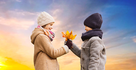 Image showing kids with autumn maple leaves over sky background