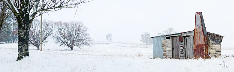 Image showing Rustic timber cabin with chimney in snowy winter landscape