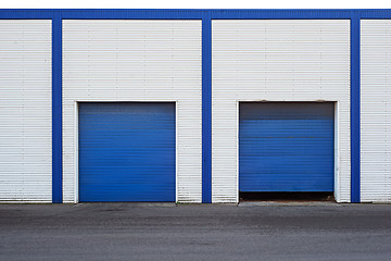 Image showing White Industrial warehouse with blue door for trucks.