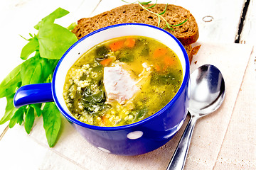 Image showing Soup with couscous and spinach in blue bowl on board