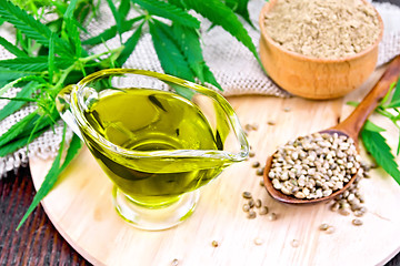 Image showing Oil hemp in sauceboat with grain on dark board