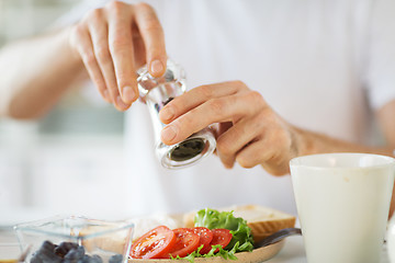 Image showing close up of hands seasoning food by pepper mill