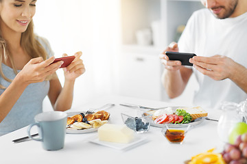 Image showing close up of couple with smartphones at breakfast