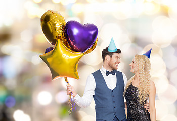 Image showing happy couple with party caps and balloons