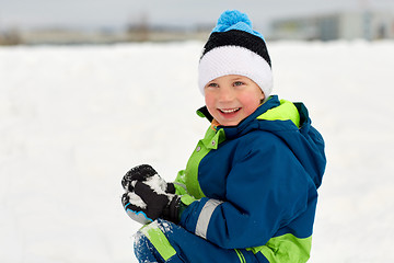 Image showing happy little boy playing with snow in winter