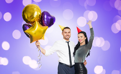 Image showing happy couple with party caps and balloons