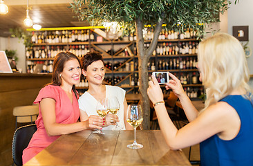Image showing woman picturing friends by smartphone at wine bar