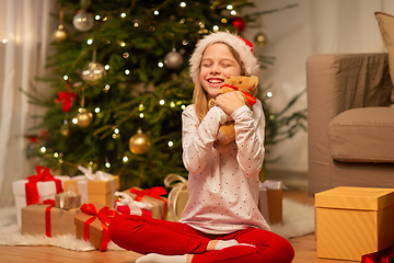 Image showing smiling girl in santa hat with christmas gift